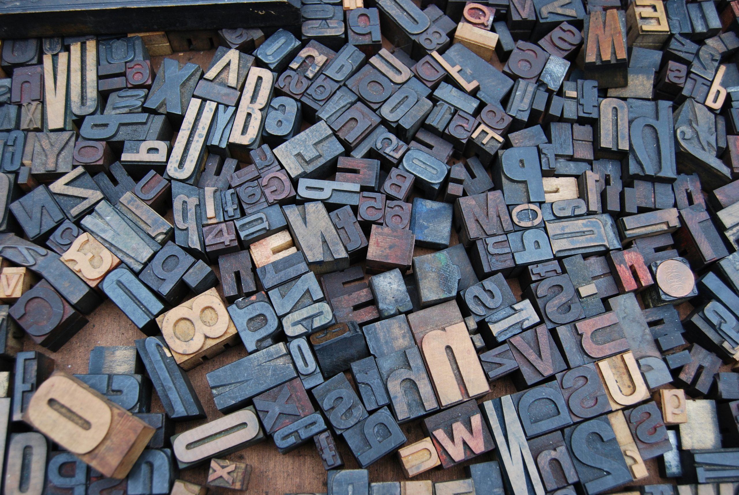 Close-up of overlapping wooden printing blocks with scattered letters